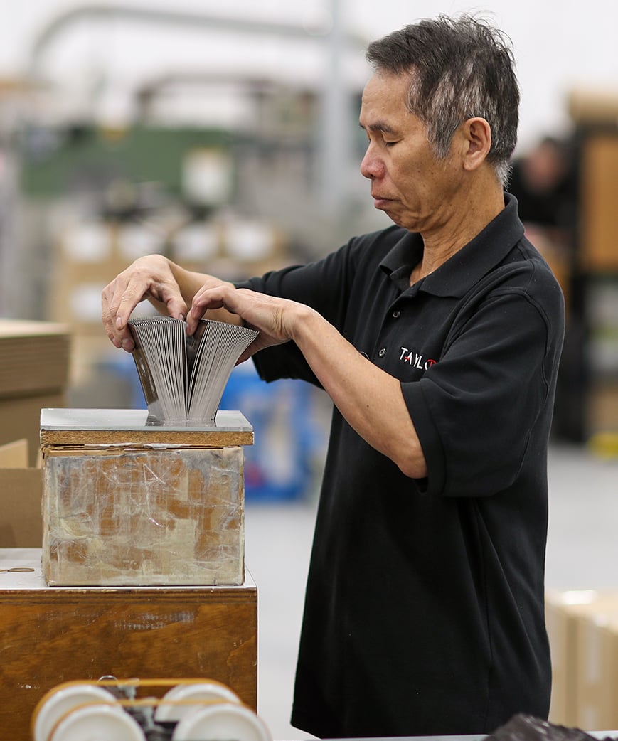 Man boxing handful of brochures in production facility