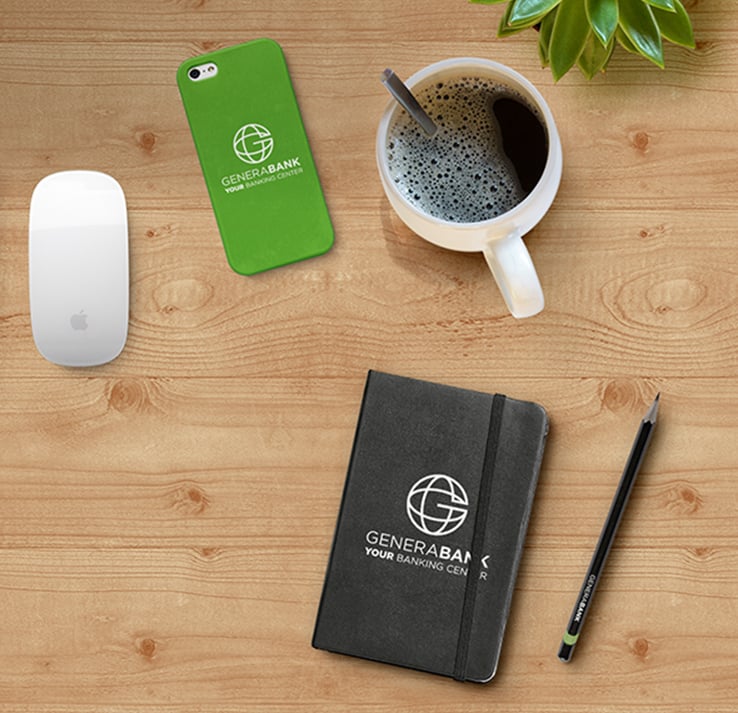 Promotional products on desk workspace with coffee mug, branded phone case, journal and pencil