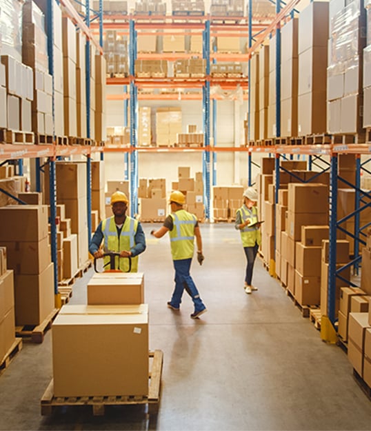 Warehouse employees surveying and moving boxes of materials to ship out to local branch locations.