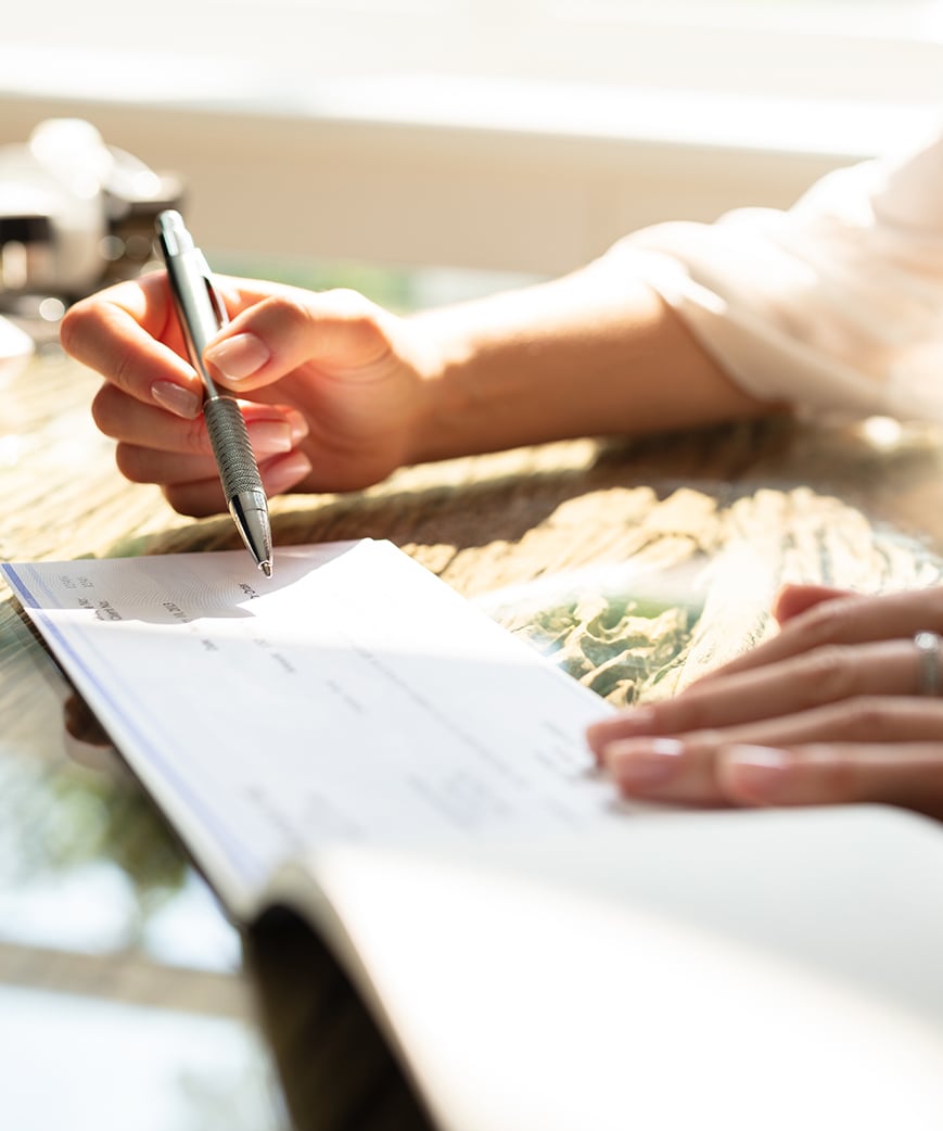 persons hands filling out checkbook