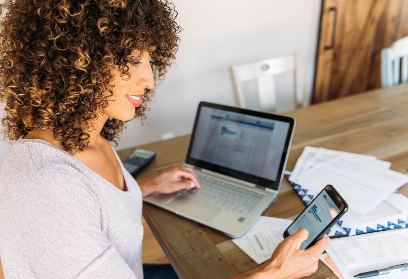 Woman browses banking website on mobile and laptop devices.